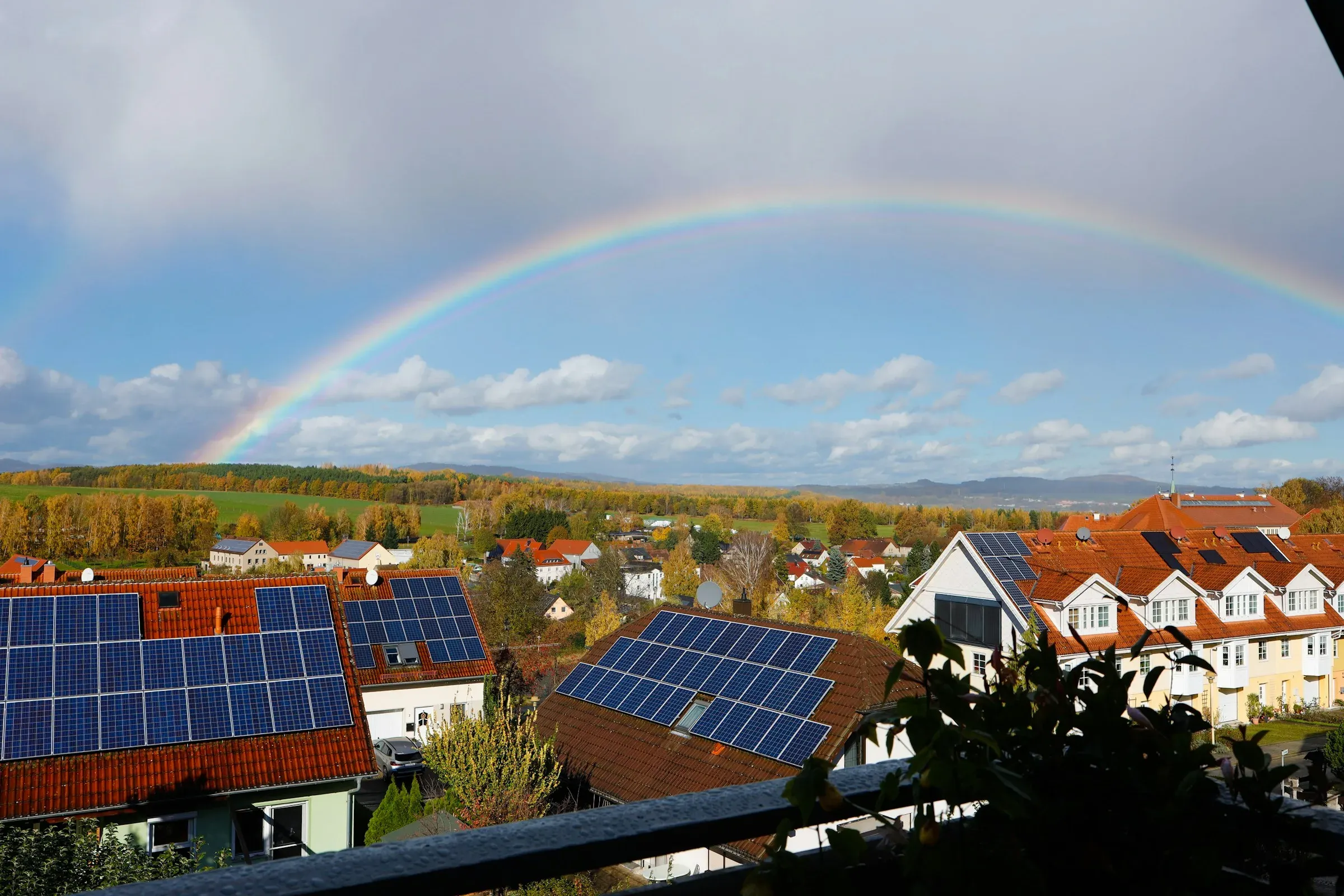 Wohnhäuser mit Photovoltaik auf den Dächern nach einem Regenschauer – die Wärmewende erreicht den Gebäudebestand