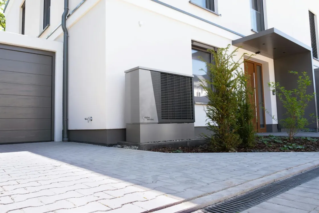 Luft-Wasser-Wärmepumpe vor einem weißen Einfamilienhaus – eine der Erfüllungsoptionen der 65-Prozent-Regel