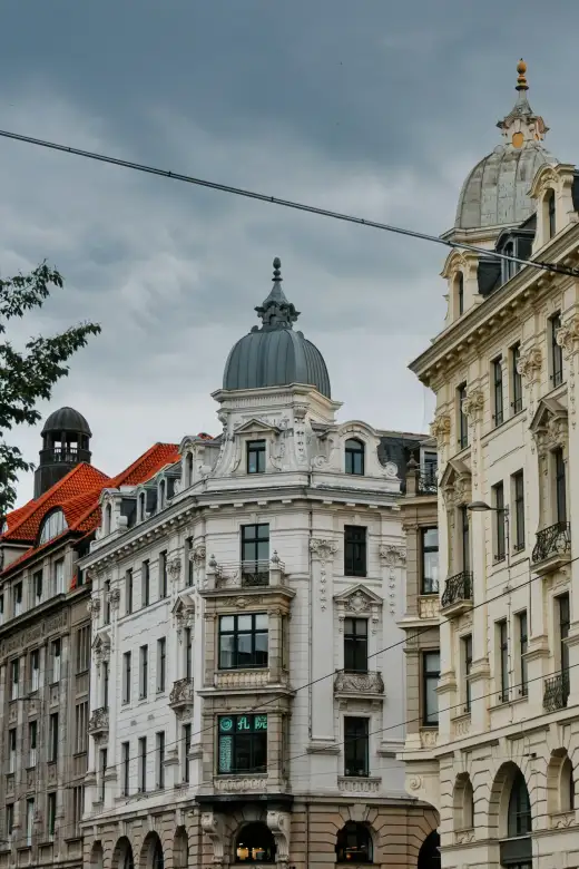 Reich verzierte Gründerzeit-Altbauten mit hellen Stuckfassaden, Erkern und geschwungenen Turmhauben stehen dicht an dicht in einem urbanen Altbauviertel – wie die typischen Wohnzeilen im Dresdner Stadtteil Löbtau.
