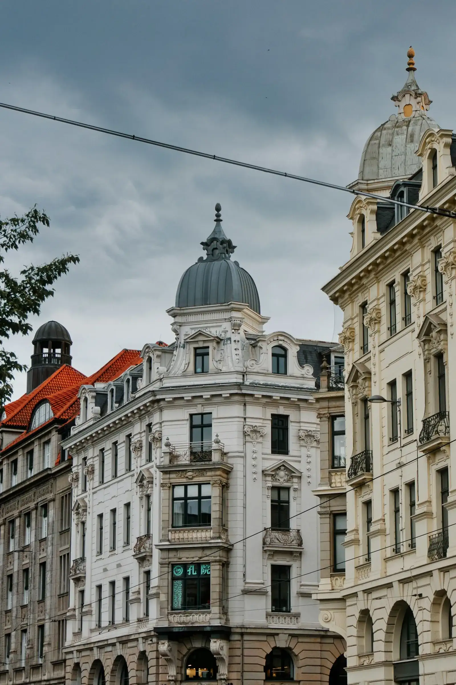 Reich verzierte Gründerzeit-Altbauten mit hellen Stuckfassaden, Erkern und geschwungenen Turmhauben stehen dicht an dicht in einem urbanen Altbauviertel – wie die typischen Wohnzeilen im Dresdner Stadtteil Löbtau.