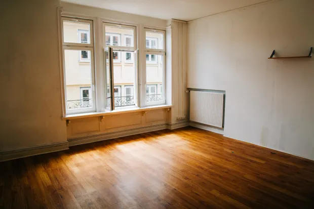 Leeres Wohnzimmer mit Dielenboden und großen Altbaufenstern – nach der Trennung stellt sich die Eigentumsfrage